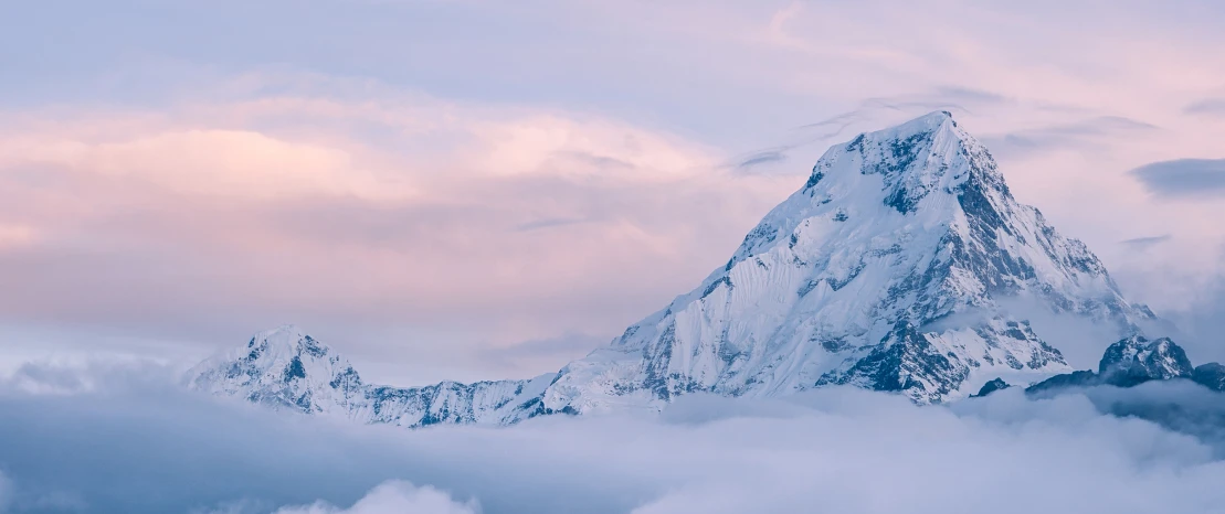 Snow-covered mountain peak above clouds at sunset