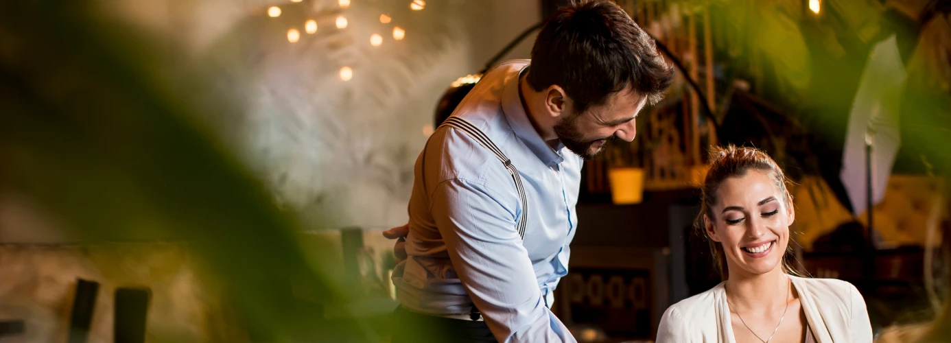 A waiter serving food to a woman in a restaurant
