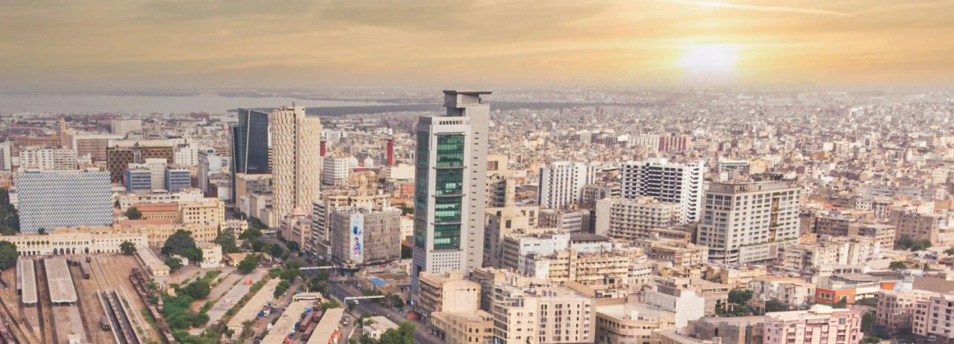 Aerial view of a densely populated city skyline with modern skyscrapers and buildings at sunset.