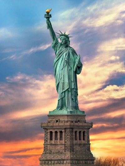 Statue of Liberty against a colorful sunset sky.